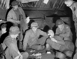 Eight soldiers play cards in their stable billet near Nancy, France, 1944. One soldier is from Irvington, Douglas County, Nebraska. Donated by PFC Lawrence E. Hansen (Hanson?).